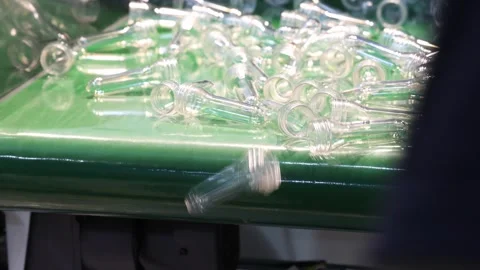 Plastic bottle preforms on conveyor belt in automated manufacturing system. Stock Footage 313344907