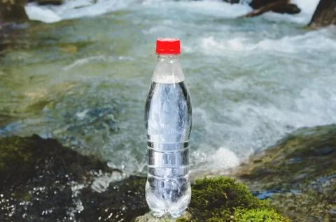 A plastic bottle with a red cap with fresh drinking water against a background Stock Photos