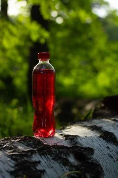 A plastic bottle with a red liquid on a log Stock Photos