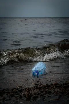 A plastic bottle by the rocks on the seashore. Garbage on the seashore Stock Photos