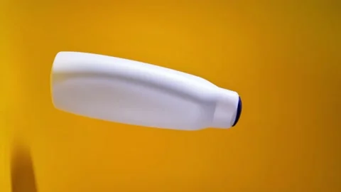 A plastic bottle rotates in the air on a yellow background Stock Footage 228481764