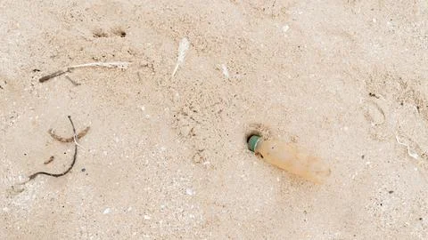 Plastic bottle on sand, pollution of the environment and the planet Stock Photos