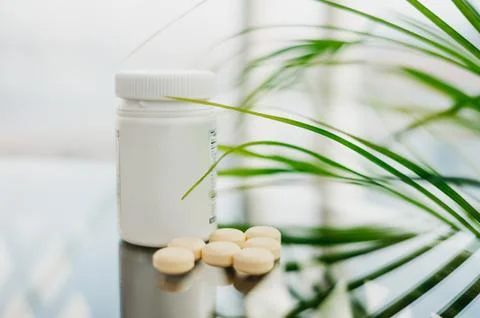 Plastic bottle with scattered light pills on the glass. Stock Photos
