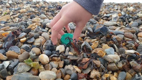 Plastic bottle top is picked up from a beach Stock Footage 119212137