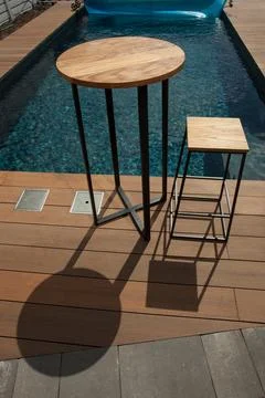 Plastic bottle of water and empty chair on balcony against swimming pool Stock Photos