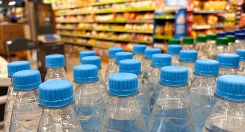 Plastic bottles with blue caps filled with clear drinking water, displayed Stock Photos