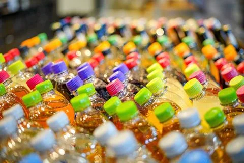 Plastic bottles with drinks with colored lids on a shop window. Stock-Fotos