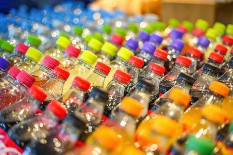 Plastic bottles with drinks with colored lids on a shop window. Foto stock