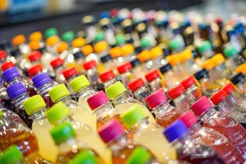 Plastic bottles with drinks with colored lids on a shop window. Stock Photos