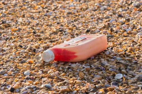Plastic bottles of engine oil on the beach is strewn with small colorful sea  Stock Photos