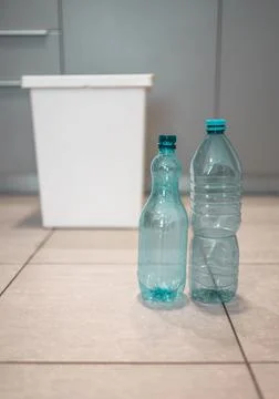 Plastic bottles next to a trash bin. Sorting plastic for easier recycling of  Stock Photos
