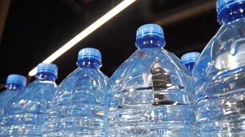 Plastic bottles of water with blue caps lined up in a grocery store Stock Footage 295303445