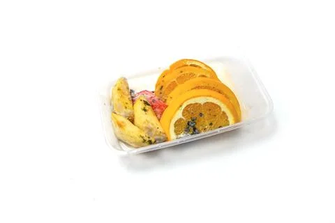 A plastic box filled with sliced oranges, rotten yellow fruits, and moldy s.. Stock Photos