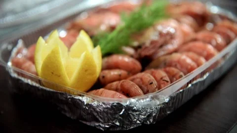 Plastic box with fried shrimp, lemon is covered by the hands of chef. HD Stock Footage 141447364