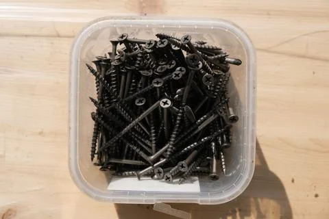 Plastic box with self-tapping screws on a wooden surface top view Stock Photos