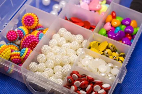 Plastic box with small accessories for needlework in separate cells on a blue Stock Photos