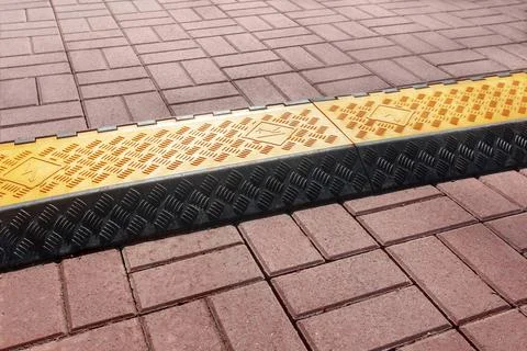Plastic box for temporary safe cable laying over the road or sidewalk. Stock Photos