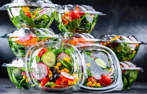 Plastic boxes with pre-packaged vegetable salads, put up for sale in a commer Stock Photos
