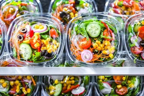 Plastic boxes with pre-packaged vegetable salads, put up for sale in a commer Stock Photos