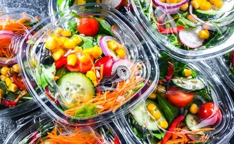 Plastic boxes with pre-packaged vegetable salads, put up for sale in a commer Stock Photos
