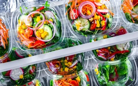 Plastic boxes with pre-packaged vegetable salads, put up for sale in a commer Stock Photos