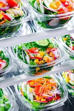 Plastic boxes with pre-packaged vegetable salads, put up for sale in a commer Stock Photos