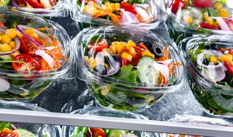 Plastic boxes with pre-packaged vegetable salads, put up for sale in a commer Foto stock