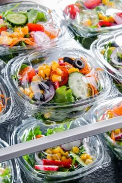Plastic boxes with pre-packaged vegetable salads, put up for sale in a commer Stock Photos