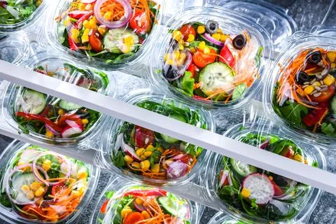 Plastic boxes with pre-packaged vegetable salads, put up for sale in a commer Stock Photos