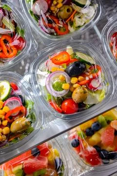 Plastic boxes with pre-packaged vegetable salads, put up for sale in a commer Stock Photos