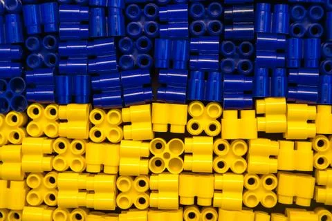 Plastic bricks are yellow and blue on a black background. Details of toys. To Stock Photos