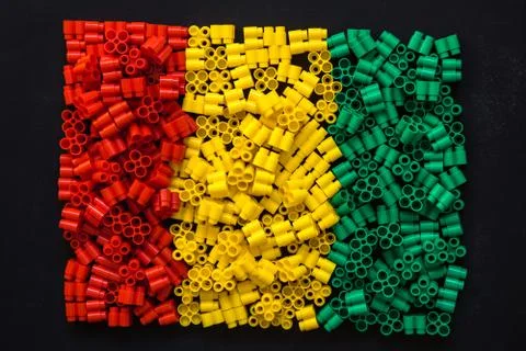 Plastic bricks of red, yellow and green on a black background. Details of toy Stock Photos