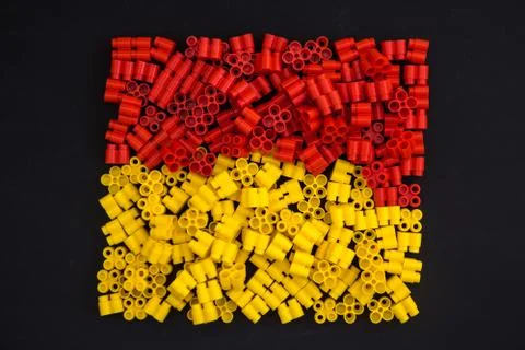 Plastic bricks of yellow and red on a black background. Details of toys. Top Stock Photos