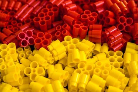 Plastic bricks of yellow and red on a background. Details of toys. Close up. Stock Photos