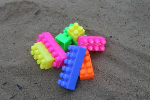 Plastic building blocks on sand background. Stock Photos