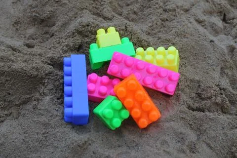 Plastic building blocks on sand background. Stock Photos