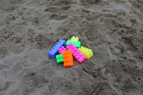 Plastic building blocks on sand background. Stock Photos