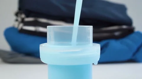 Plastic cap is filled with blue liquid laundry detergent Stock Footage 152618348