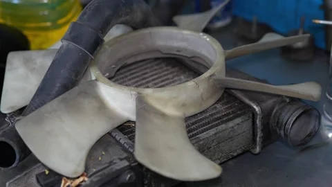 A plastic car radiator cooling fan blade unit lies on top of a detached metal Stock Footage 345108488