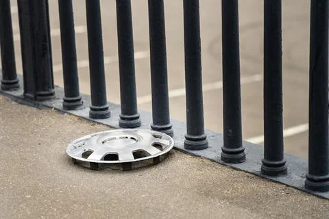 Plastic car wheel hubcap lying on the sidewalk after a road traffic acciden.. Stock Photos