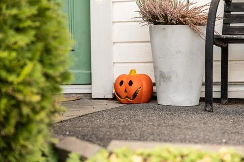 Plastic carved pumpkin placed by the steps of a green door. Stock Photos