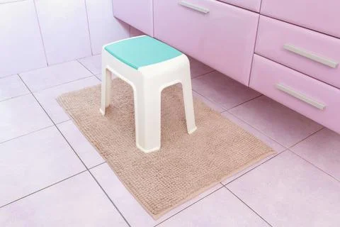 Plastic chair on rectangle beige carpet in bathroom Stock Photos