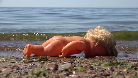 Plastic child's doll laying face down on the beach Stock Footage 239612277