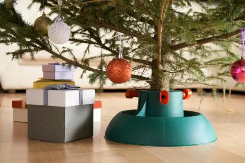 Plastic Christmas tree stand surrounded by gift boxes stands at home in New Year 写真素材