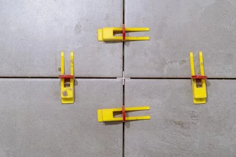 Plastic clips and wedges securing tiles in place for perfect alignment. Stock Photos