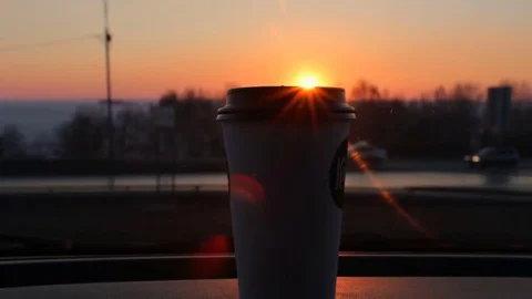 Plastic coffee cup standing on car panel sunset and city road traffic background Stock-Footage 74999260