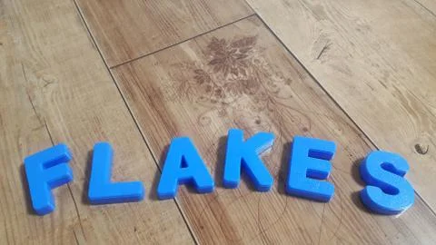 Plastic colored alphabets making words are placed on a wooden floor Stock Photos