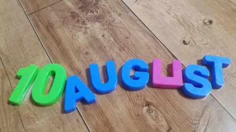 Plastic colored alphabets making words 10 August are placed on a wooden floor Stock Photos