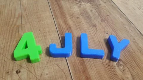 Plastic colored alphabets making words 4 july are placed on a wooden floor Stock Photos