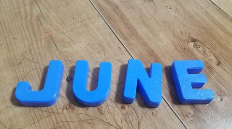 Plastic colored alphabets making words June are placed on a wooden floor Stock Photos